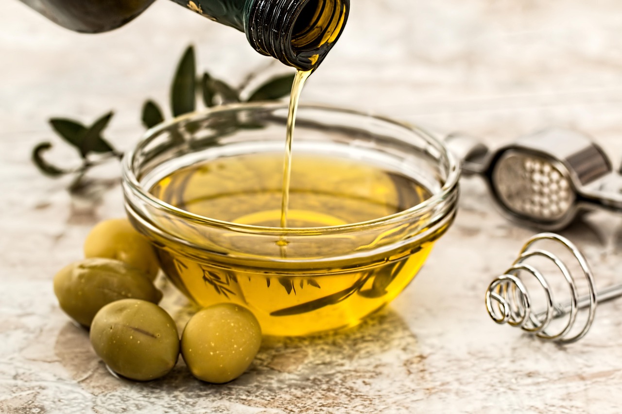 Olio extravergine d'oliva versato in un cucchiaio, simbolo di salute e benefici quotidiani.