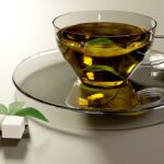Tazza di tè verde fumante su un tavolo, con fette di limone e un libro aperto accanto.