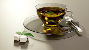Tazza di tè verde fumante su un tavolo, con fette di limone e un libro aperto accanto.