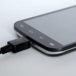 Caricabatterie del telefono collegato alla presa elettrica durante la notte, con bolletta in evidenza.