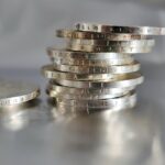 Bilancia che pesa 100 grammi di argento con monete e grafico dei prezzi.