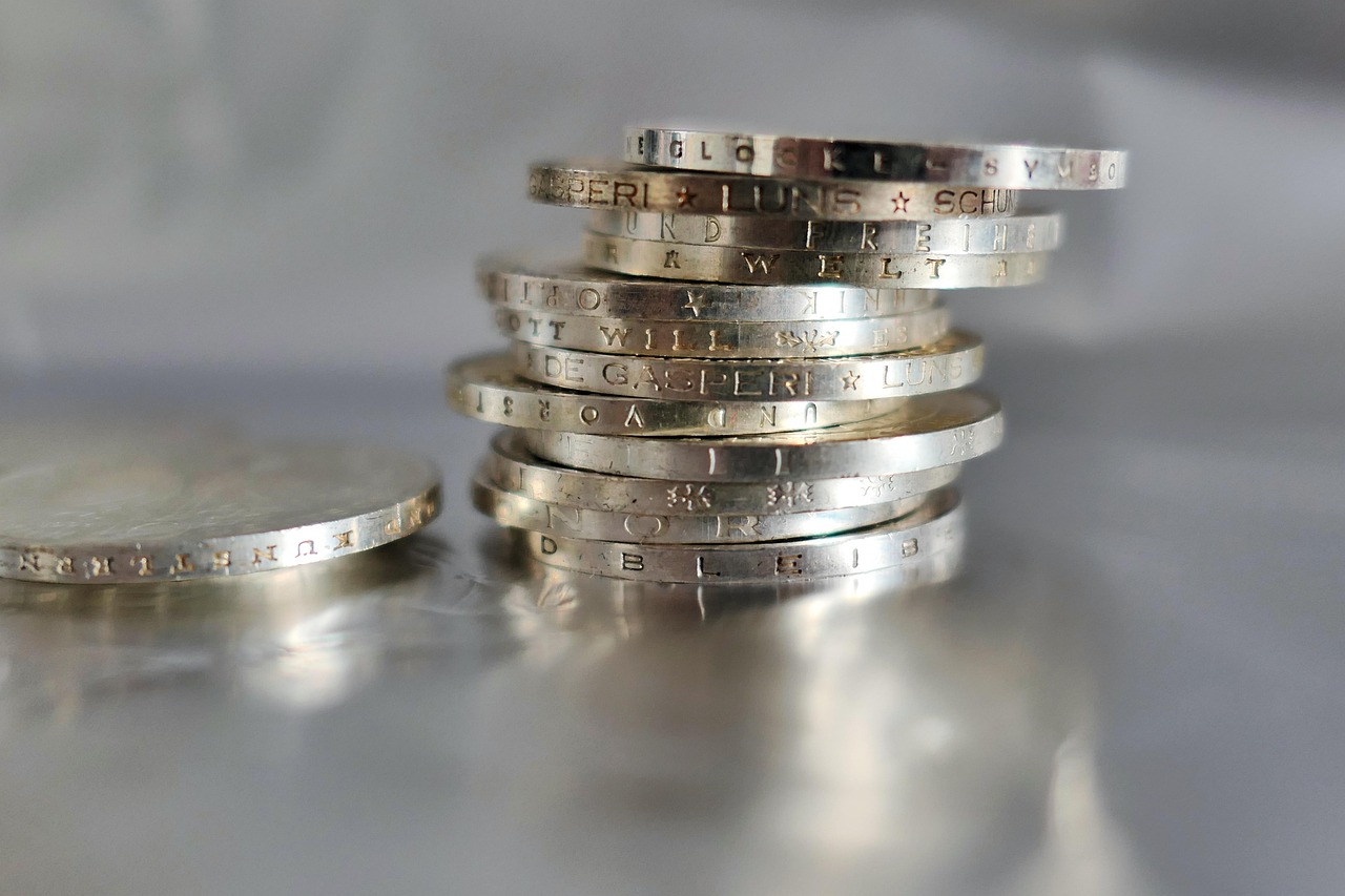 Bilancia che pesa 100 grammi di argento con monete e grafico dei prezzi.